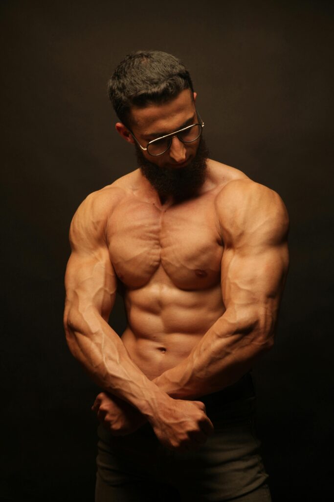 Studio shot of a shirtless muscular man flexing his muscles showing strength and fitness.
